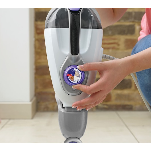 Close-up photo of a hand adjusting the control dial on a BLACKDECKER steam mop BHSM1615DSM.