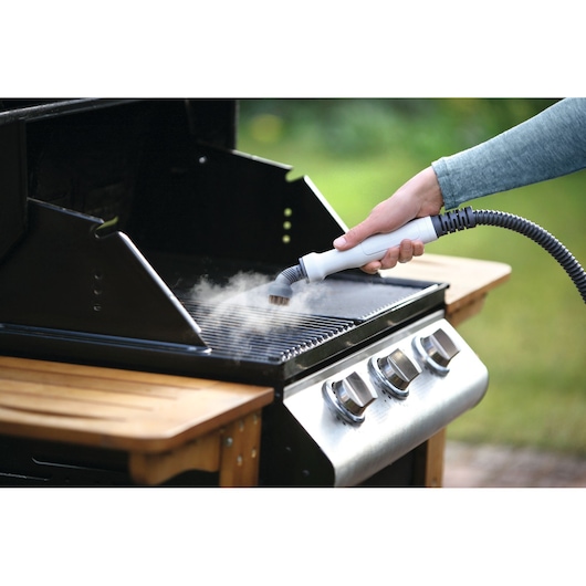 Photo of BLACKDECKER BHSM1615DSM handheld steam cleaner being used to clean an outdoor barbecue grill.