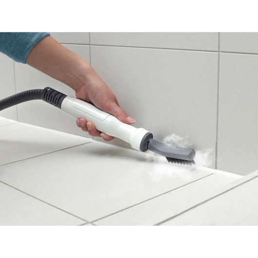 BLACKDECKER BHSM166DSM steam cleaner with brush attachment cleaning white tile grout.