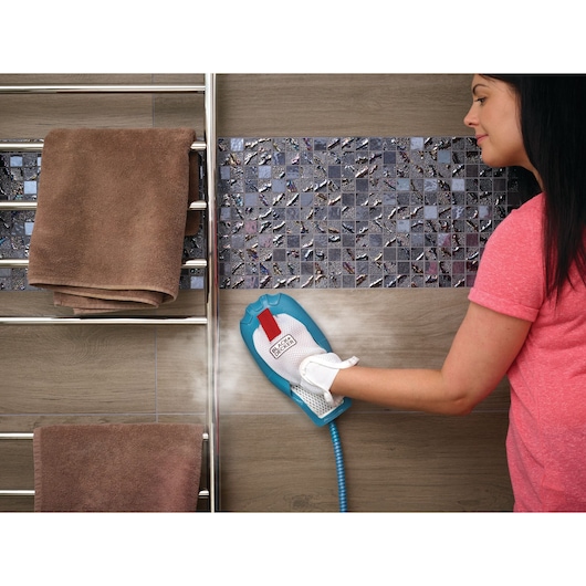 Photo of BLACK+DECKER BHSM166DSM steam cleaning glove cleaning bathroom tile wall near a towel rack.