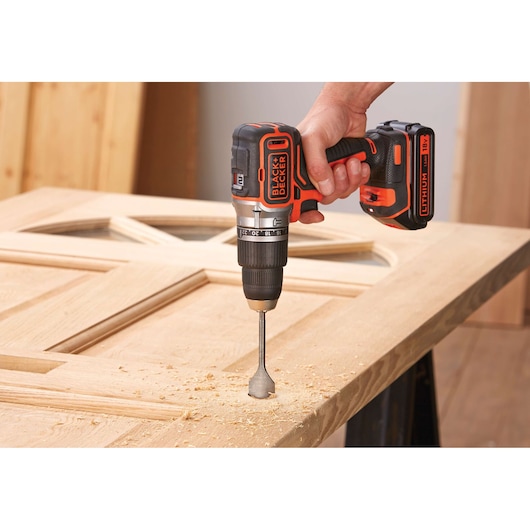 BLACKDECKER BL188KB cordless drill in use on wooden door, close-up of hand and tool.