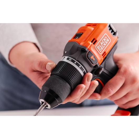 Close-up photo of BLACK+DECKER cordless drill BLD683XN, orange and black, being adjusted by hand.