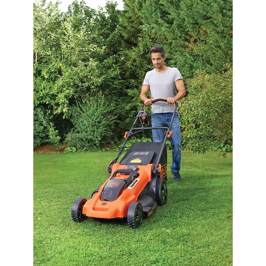 Photography of BLACKDECKER CLMA4825L2 lawn mower in use on grass, orange and black color, garden setting