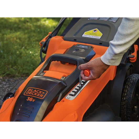 BLACKDECKER CLMA4825L2 lawn mower close-up with hand adjusting height lever outdoors.