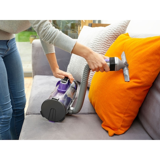 BLACKDECKER CUA625BHP vacuum cleaner used on orange cushion, sofa cleaning, photography scene.