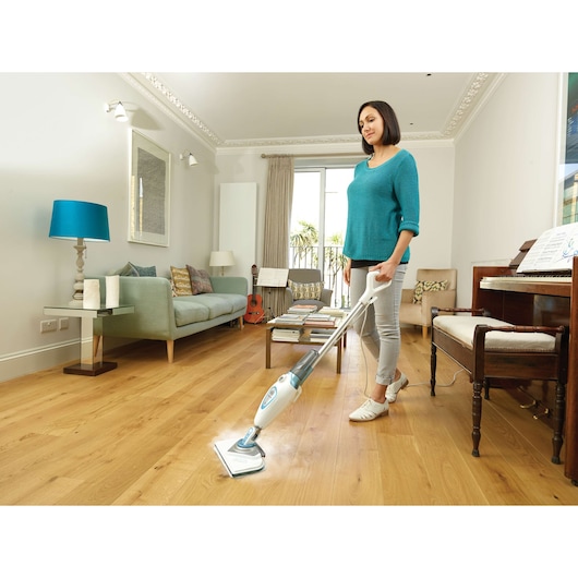 BLACKDECKER FSM1616 steam mop cleaning hardwood floor in modern living room with turquoise decor.