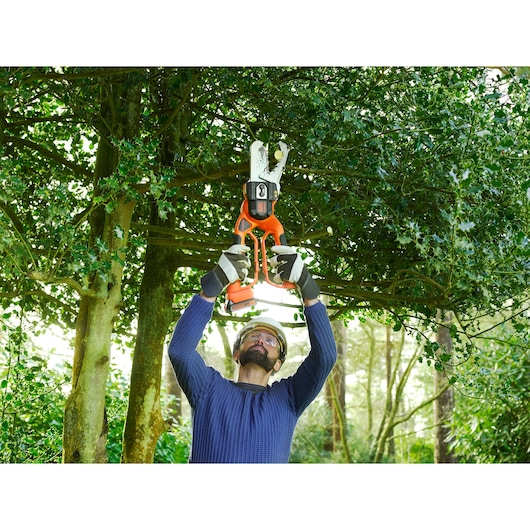 BLACKDECKER GKC1000L cordless pruner used outdoors for cutting tree branches.