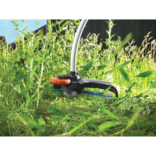 BLACKDECKER GL8033 grass trimmer cutting tall grass outdoors, close-up view of trimming head.