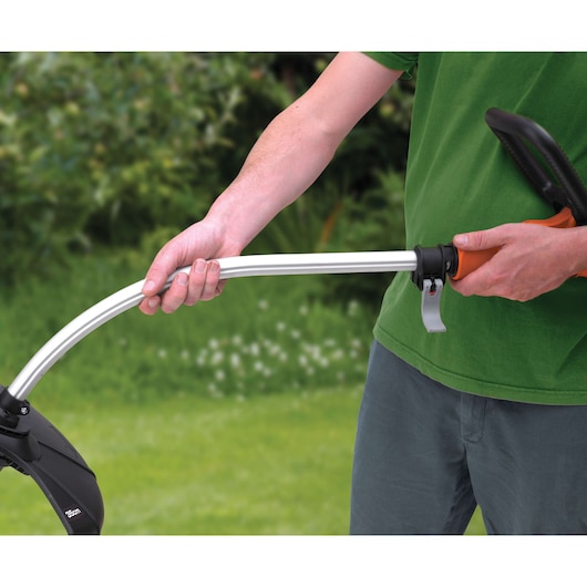 Photo of person holding BLACKDECKER GL8033 string trimmer handlebar outdoors.