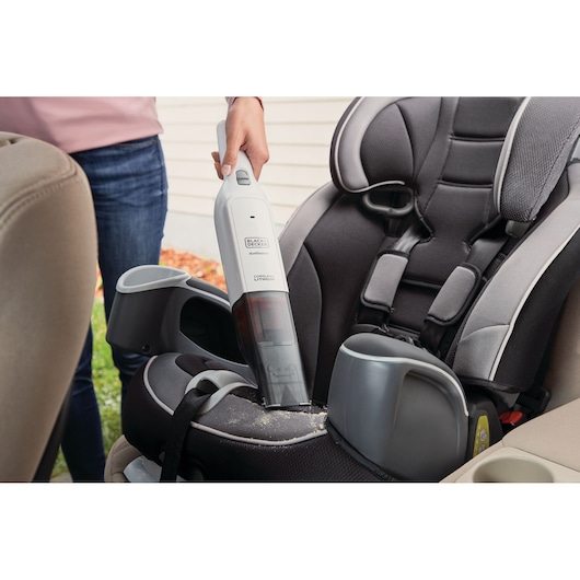 BLACKDECKER HLVC315B11 handheld vacuum cleaning car seat, gray and white unit photographed in action.
