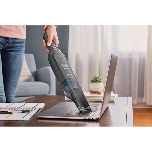BLACK+DECKER HLVC320B11 cordless handheld vacuum cleaning laptop keyboard on desk.
