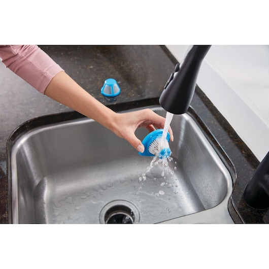 BLACKDECKER HLVC320J11 kitchen brush accessory being rinsed under faucet in stainless steel sink