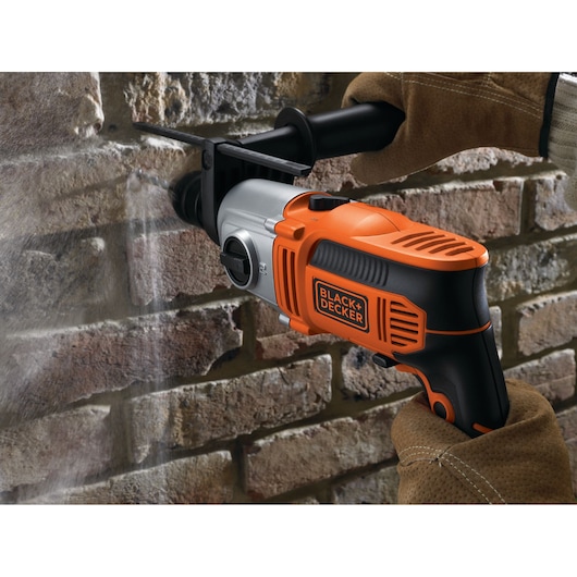 BLACK+DECKER KR8542BK hammer drill with orange and black casing in use drilling into brick wall.