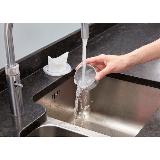 BLACKDECKER NVC115JL filter being rinsed under faucet in kitchen sink, photography angled view
