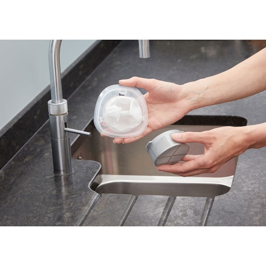 Photo of BLACKDECKER NVC115W handheld vacuum filter being cleaned at a kitchen sink.
