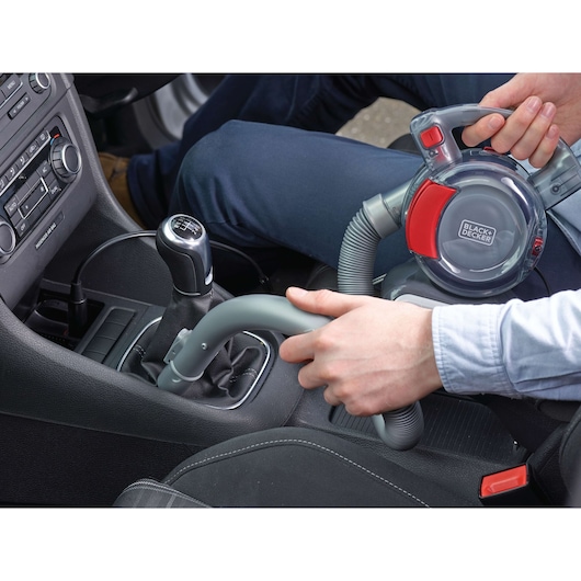BLACKDECKER PD1200AV handheld car vacuum in use cleaning a car interior, flexible hose visible.