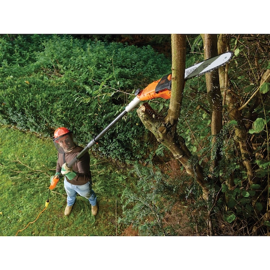 BLACKDECKER PS7525 pole saw used for pruning branches in a garden, orange and black design.