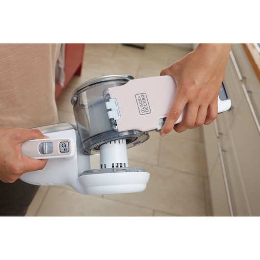 BLACKDECKER PV1820LRGP handheld vacuum cleaner being opened for emptying, close-up of dust container in kitchen.