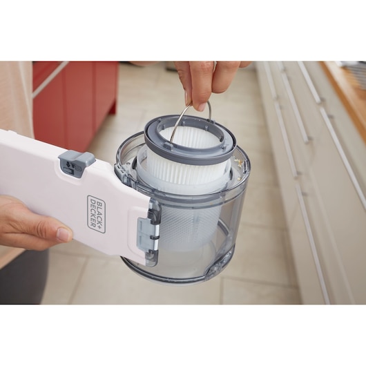 Photo of BLACK+DECKER PV1820LRGP handheld vacuum dust container with filter being removed in a kitchen setting.