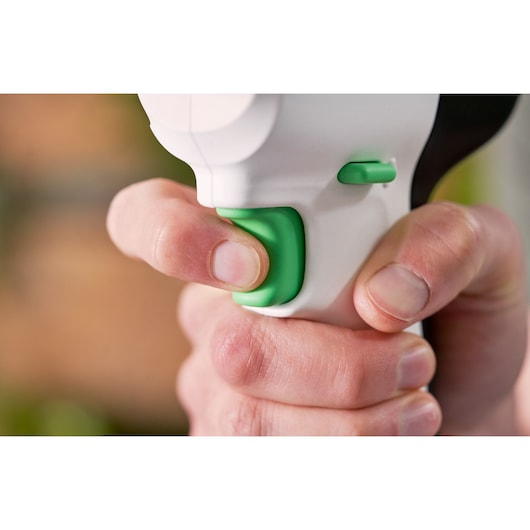 Close-up photo of a hand pressing the green trigger on a BLACKDECKER REVDD12C power tool handle.