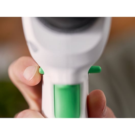 Closeup of hand holding BLACKDECKER REVDD12C drill, focusing on green trigger and buttons.
