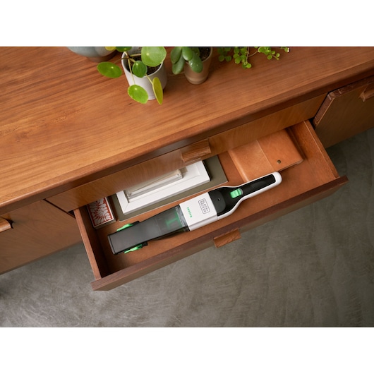 BLACK+DECKER REVHV8C handheld vacuum cleaner stored in a wooden drawer, white and black design with green accents.