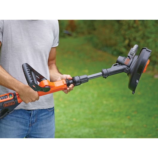 Photo of BLACKDECKER STC1840EPC grass trimmer in use outdoors, orange and black, ergonomic handle visible.