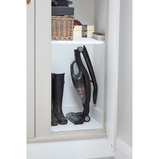 BLACKDECKER SVB620JW cordless stick vacuum cleaner stored upright in a closet next to black boots.