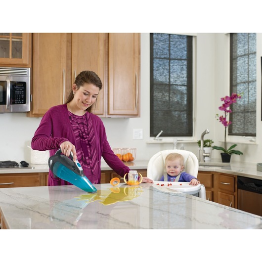 BLACKDECKER WDA320J wet and dry handheld vacuum cleaning spill on kitchen counter near baby in high chair.