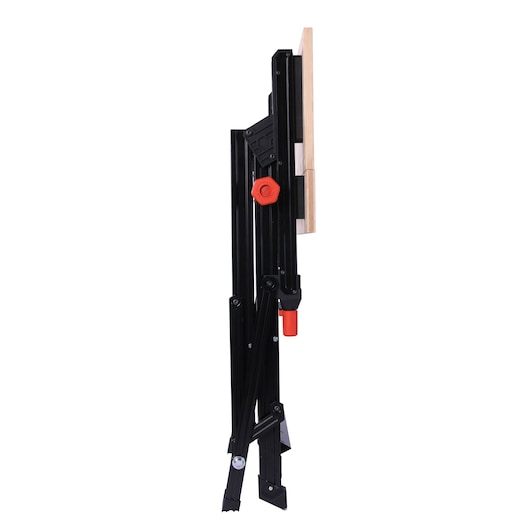 Folded BLACK+DECKER WM1000 workbench, showing side view with black metal frame and wooden top, featuring red adjustment knobs.