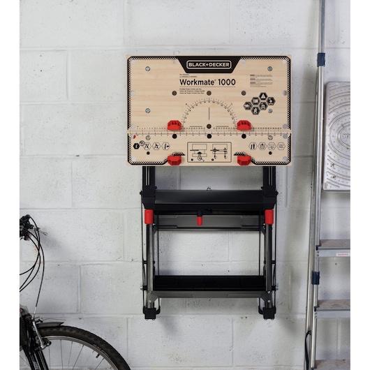 BLACK+DECKER WM1000 portable workbench with wood top and red adjustment knobs, mounted on a wall.